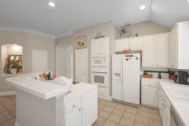 a kitchen with white cabinets and refrigerator