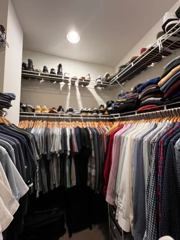 a view of walk in closet with clothes and shoes