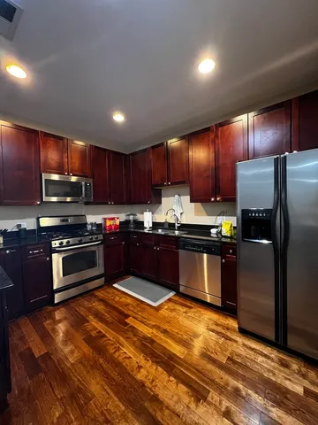 a kitchen with stainless steel appliances kitchen island granite countertop a stove refrigerator and cabinets