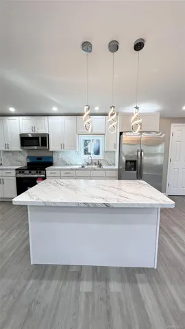 a living room with kitchen island a sink and a stove with wooden floor