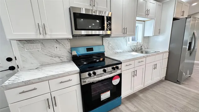 a kitchen with stainless steel appliances granite countertop a stove a microwave and a white cabinets