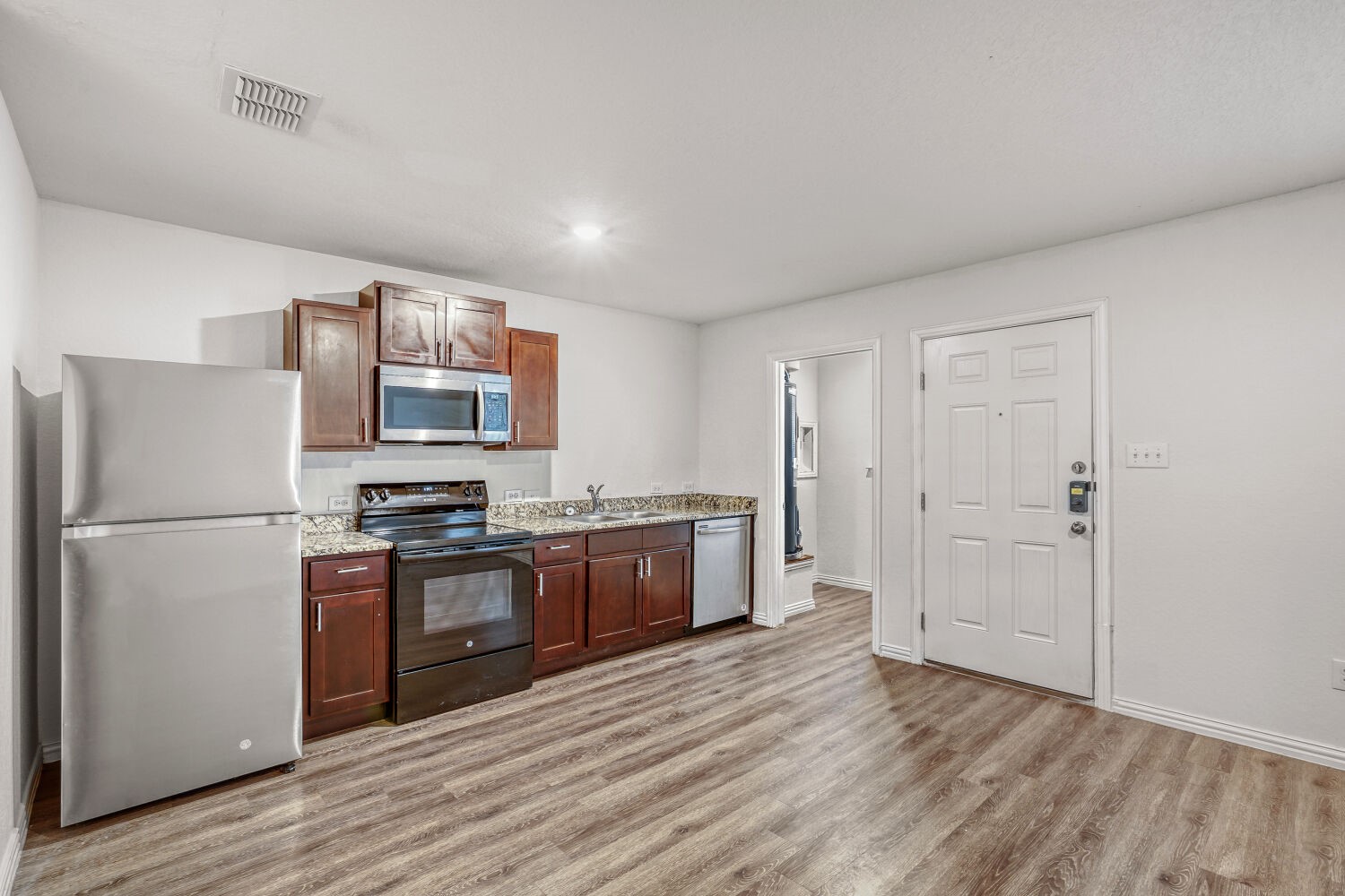 5626 Simsdale Street Houston, TX 77033 - Photo 3 of 10 a kitchen with stainless steel appliances a refrigerator and wooden floor