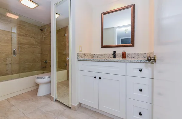 a bathroom with a granite countertop toilet a sink and a mirror