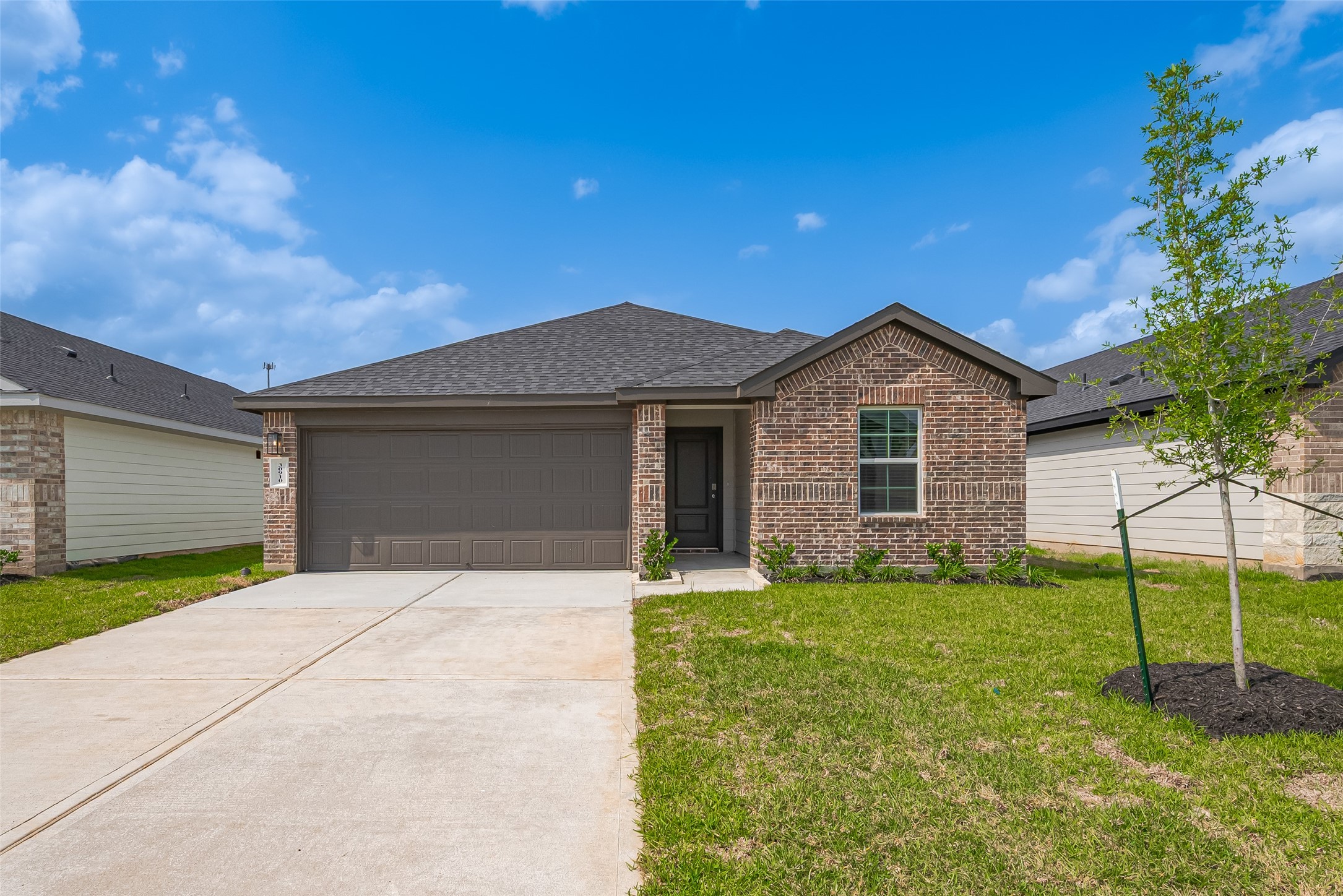 30910 Rockstock Road Fulshear, TX 77441 - Photo 33 of 33 A smooth, wide driveway leads to the two-car garage, where the rich-toned garage door complements the front entryway tucked into the facade. A young tree and neatly manicured lawn add fresh curb appeal to the timeless brick exterior.