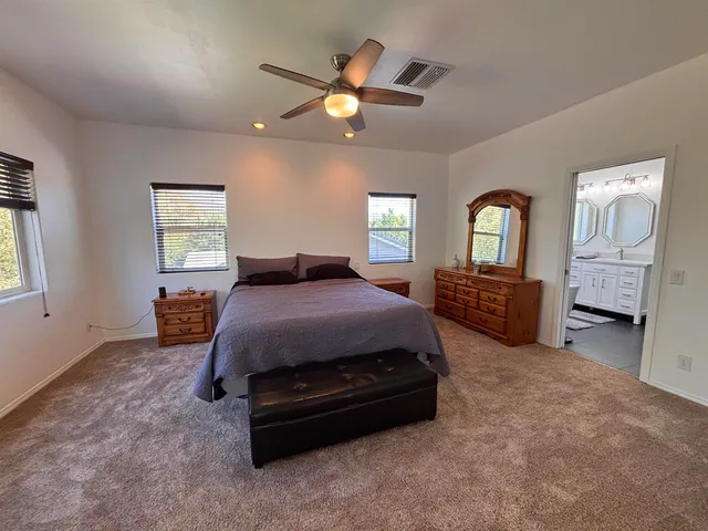 a spacious bedroom with a bed a dresser and next to a window