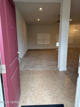 an empty room with chandelier fan and windows