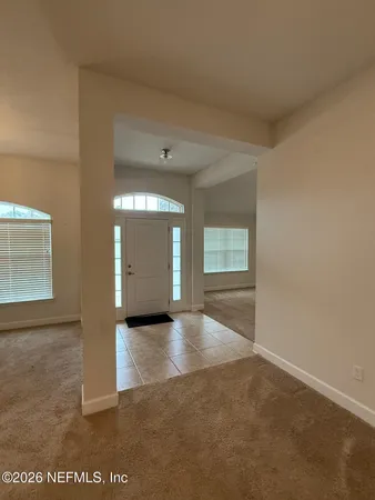 a view of an empty room and a kitchen