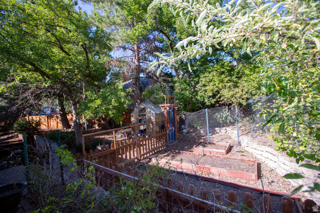 1500 Sumac Drive Logan, UT 84321 - Photo 9 of 42 Lush, treed backyard featuring a fenced garden area, raised garden beds, wood fencing, and a small utility structure