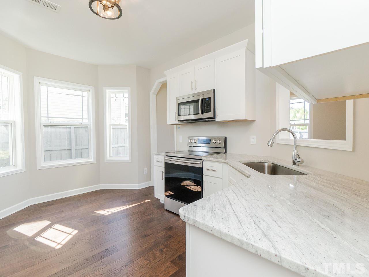 3958 Patriot Ridge Court Raleigh, NC 27610 - Photo 8 of 28 a kitchen with granite countertop a stove top oven a sink dishwasher and a microwave oven with white cabinets