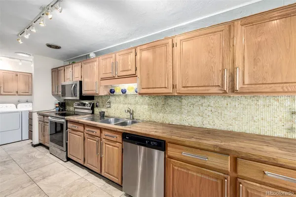 a kitchen with kitchen island granite countertop a sink stainless steel appliances and cabinets