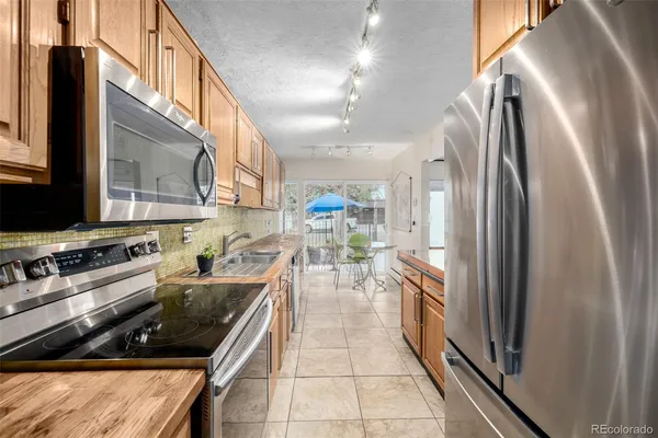 a kitchen with stainless steel appliances granite countertop a refrigerator a stove and a sink