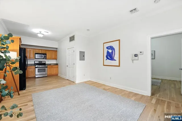 a view of a livingroom with wooden floor and a kitchen