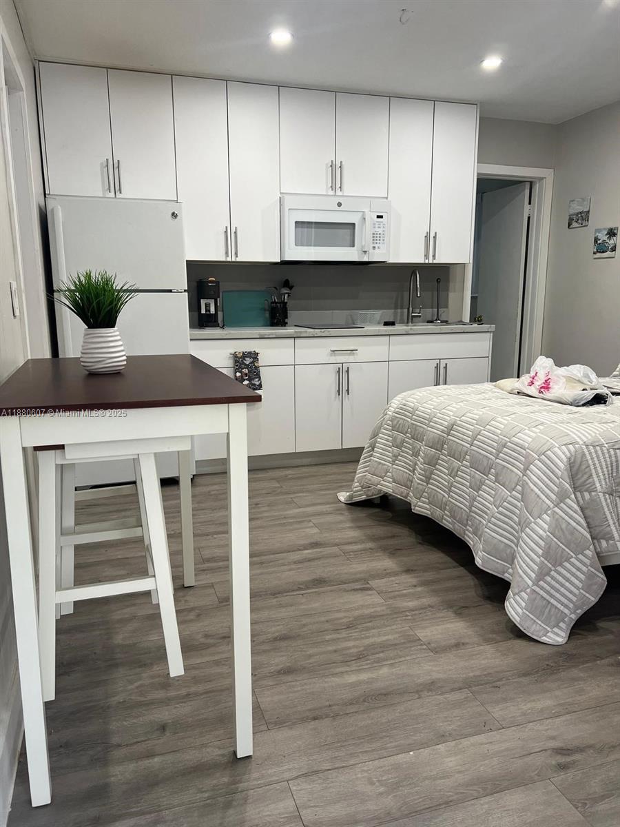 a kitchen with stainless steel appliances kitchen island granite countertop a stove a sink and white cabinets