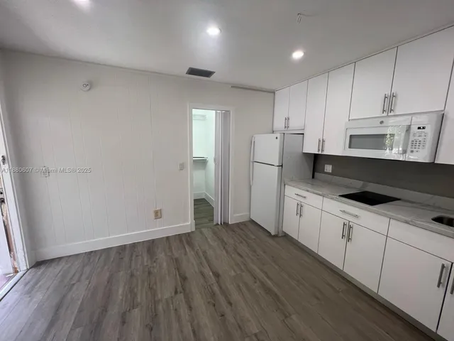a kitchen with granite countertop white cabinets and refrigerator