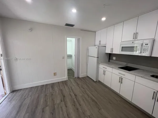 a kitchen with granite countertop white cabinets and refrigerator