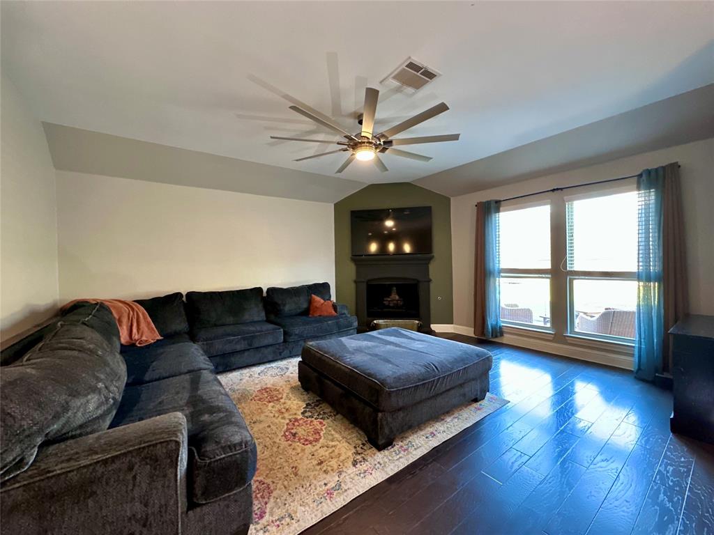 4005 Wavertree Road Frisco, TX 75036 - Photo 6 of 14 Vaulted ceiling with a ceiling fan, dark wood-finish flooring, a fireplace with a mantel, and large windows