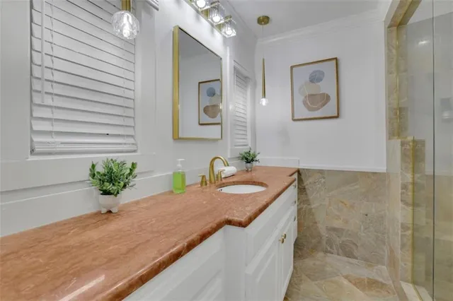 a bathroom with a granite countertop sink a mirror and a shower