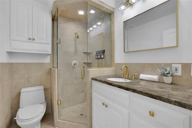 a bathroom with a granite countertop sink a toilet a mirror and shower
