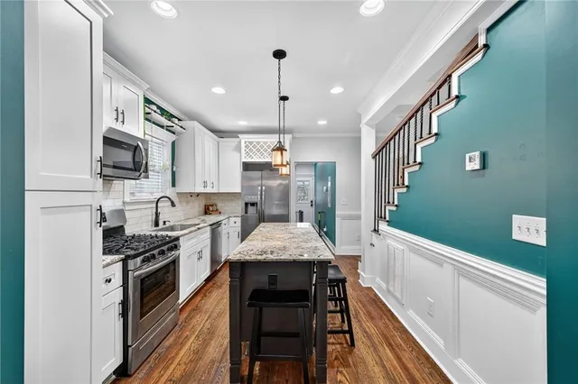 a kitchen with stainless steel appliances granite countertop a stove a sink dishwasher and a refrigerator with wooden floor