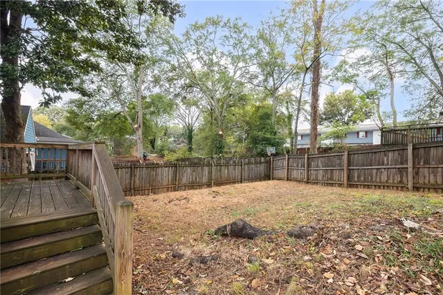 a view of backyard with wooden fence and trees