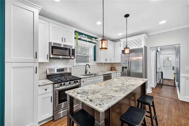 a kitchen with kitchen island granite countertop a sink appliances and wooden floor