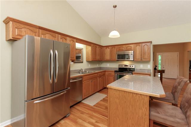 7876 Oscar Green Road Primm Springs, TN 38476 - Photo 8 of 20 Kitchen features island with bar stool area. Stainless steel appliances: dishwasher, refrigerator, smooth top stove/oven & over the range microwave