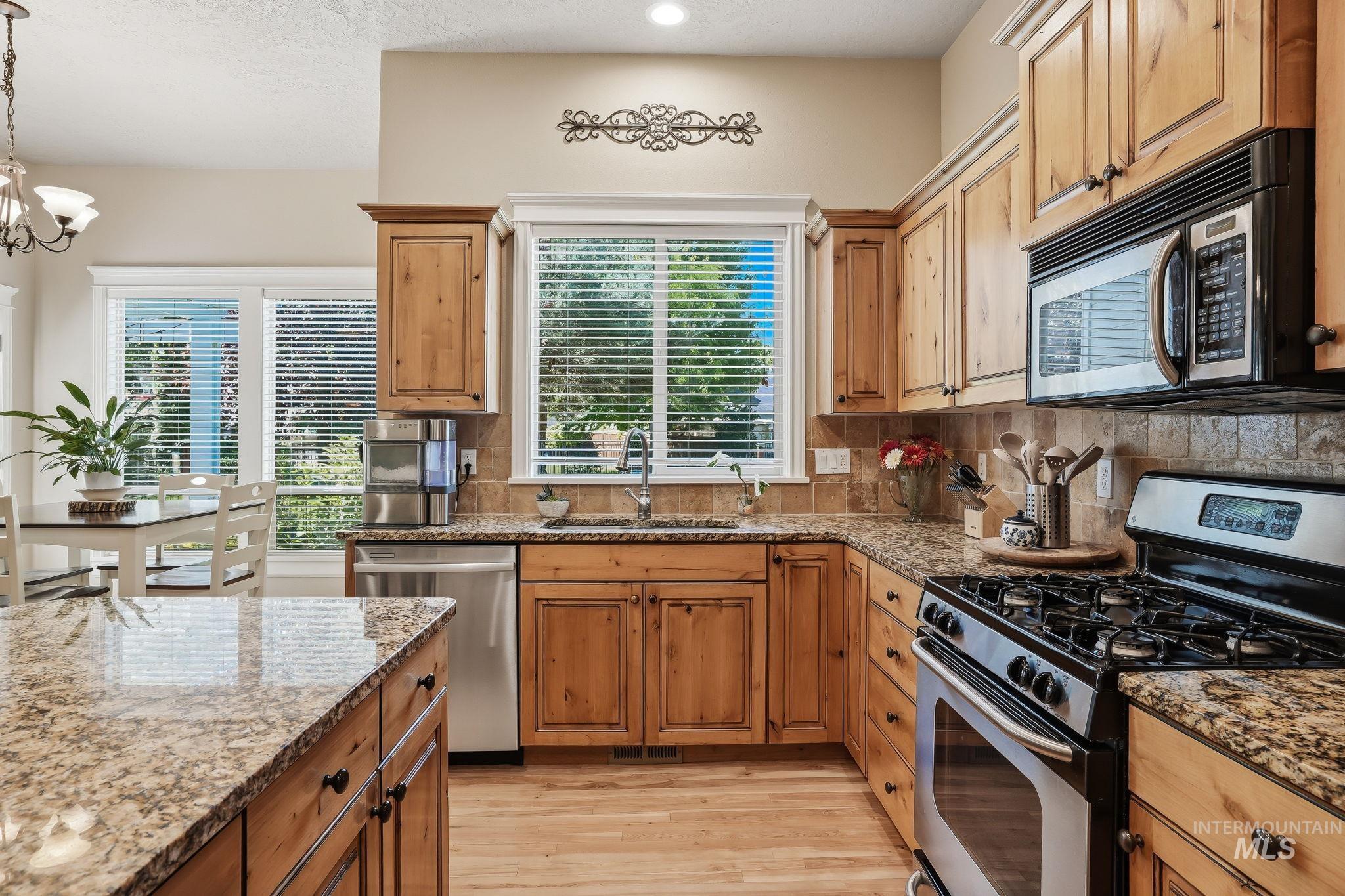 3969 North Hollymount Way Meridian, ID 83646 - Photo 11 of 47 Kitchen featuring light wood cabinetry, granite-finish countertops, stainless steel appliances, and wood-finish flooring