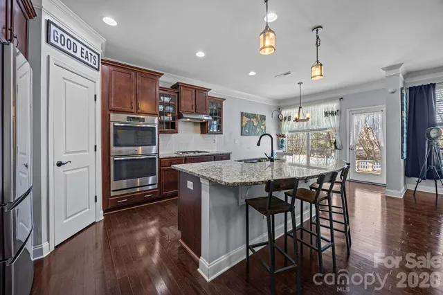 a open kitchen with stainless steel appliances granite countertop a stove refrigerator and chairs
