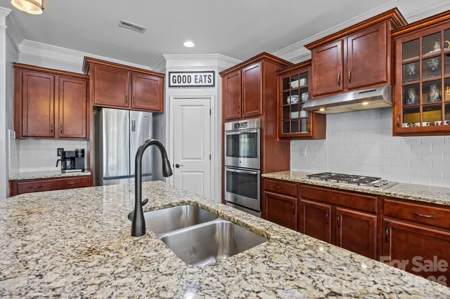 a kitchen with stainless steel appliances granite countertop a stove a sink dishwasher and a refrigerator with wooden cabinets