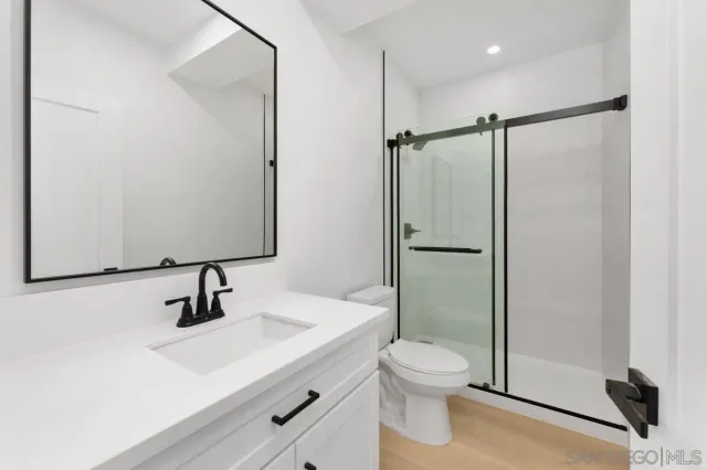 a bathroom with a shower sink vanity mirror and toilet