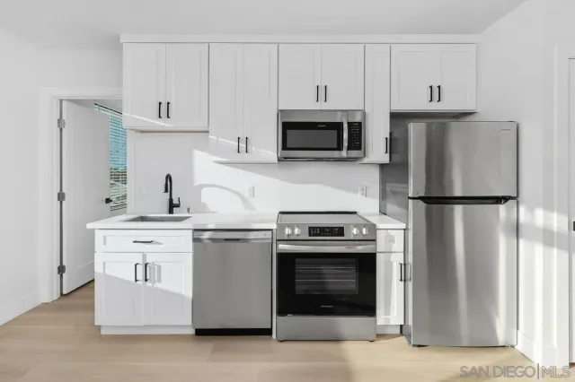 a kitchen with white cabinets and stainless steel appliances