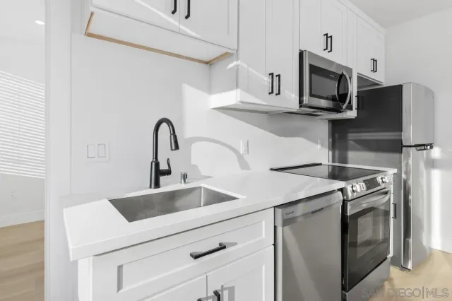 a kitchen with stainless steel appliances granite countertop a sink and a stove top oven with wooden floor