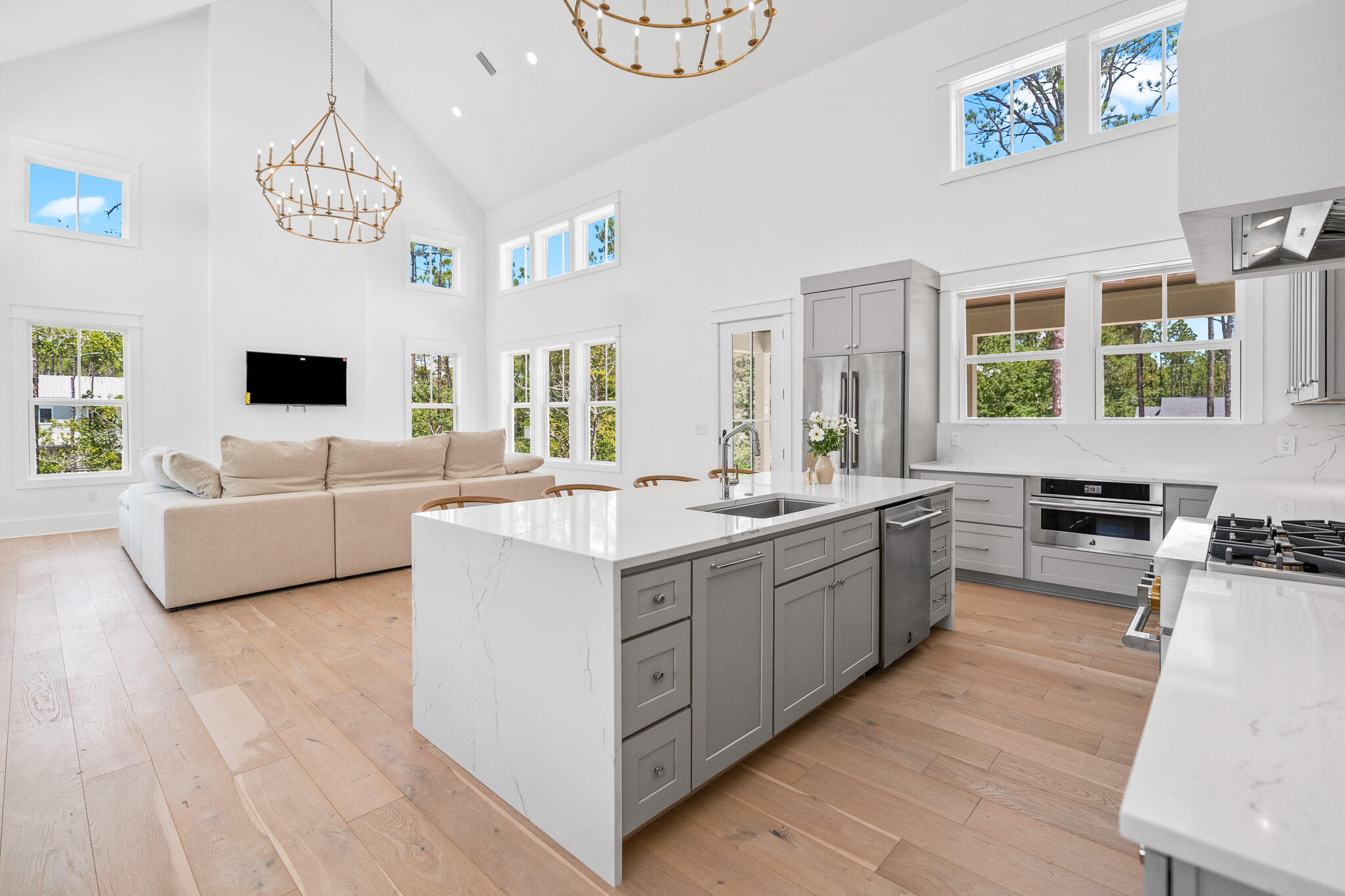 121 West Nursery Road Santa Rosa Beach, FL 32459 - Photo 19 of 66 a large white kitchen with stainless steel appliances granite countertop a sink a stove a chimney a couch and a dining table with wooden floor