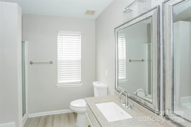 a bathroom with a granite countertop sink toilet a mirror and shower