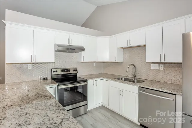 a kitchen with granite countertop a stove sink and cabinets