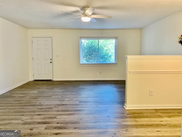 a view of an empty room with wooden floor and a window