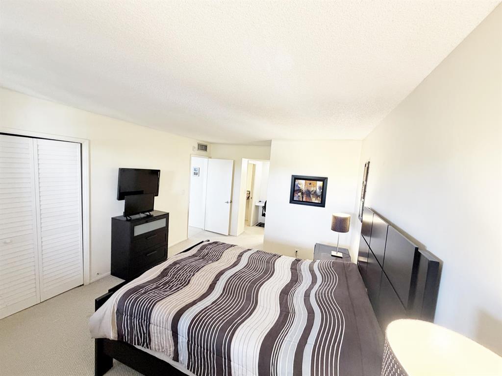 2681 South Course Drive, Unit 511 Pompano Beach, FL 33069 - Photo 18 of 35 a bedroom with a bed and a flat screen tv