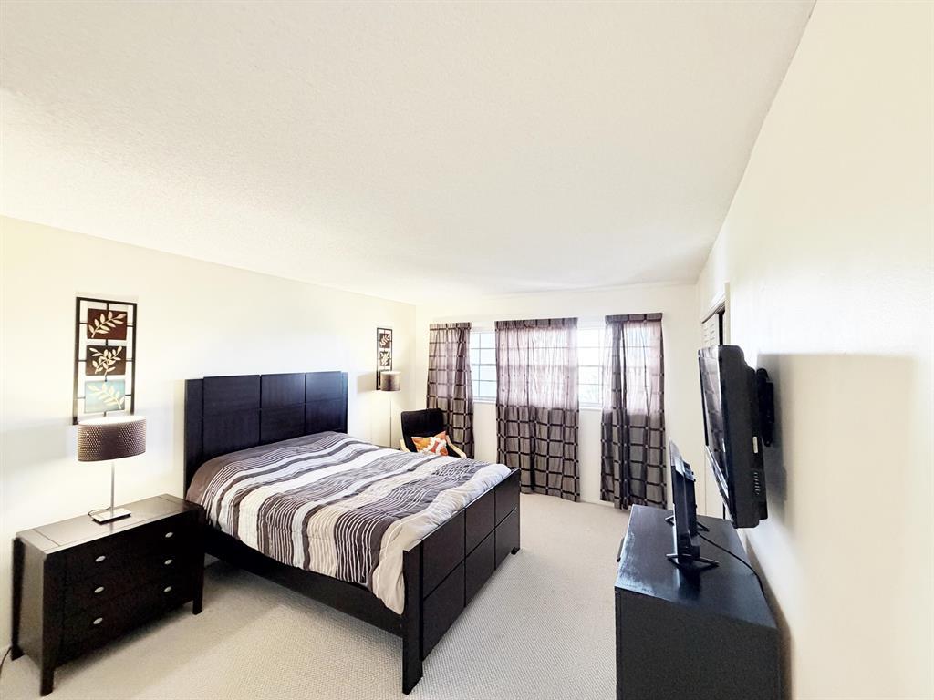2681 South Course Drive, Unit 511 Pompano Beach, FL 33069 - Photo 20 of 35 a bedroom with a bed and a flat tv screen on the dresser