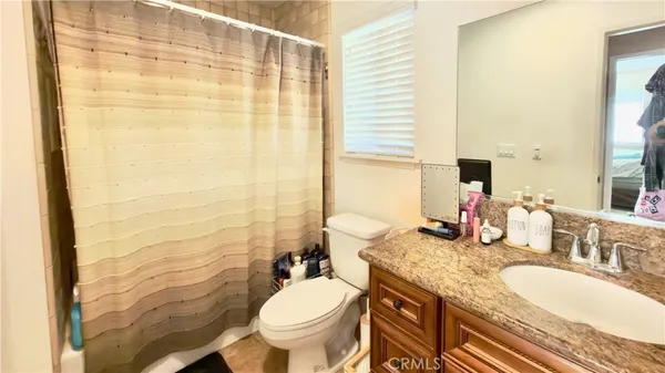 a bathroom with a granite countertop sink and a mirror with toilet