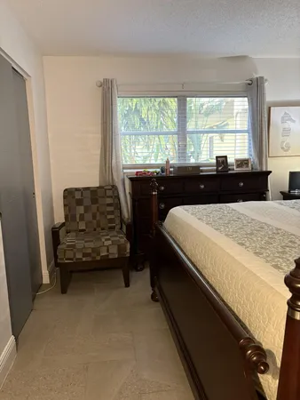 a living room with a bed and a dresser next to a window