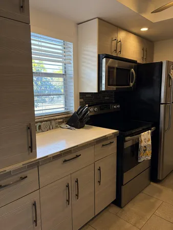 a kitchen with granite countertop white cabinets and black stainless steel appliances