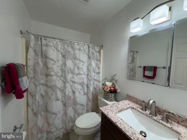 a bathroom with a granite countertop sink a toilet and a mirror