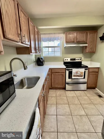 a kitchen with granite countertop a stove a sink and a microwave