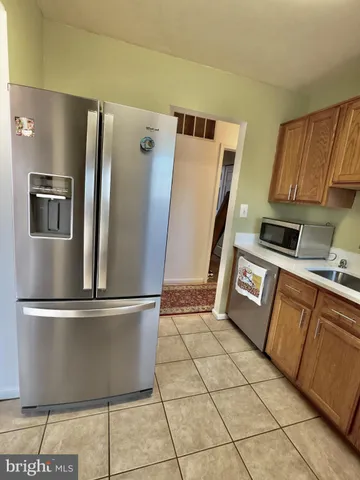 a view of a refrigerator in kitchen and an empty room