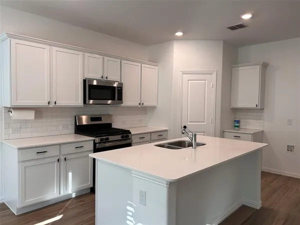 a kitchen with a sink a stove a microwave and cabinets