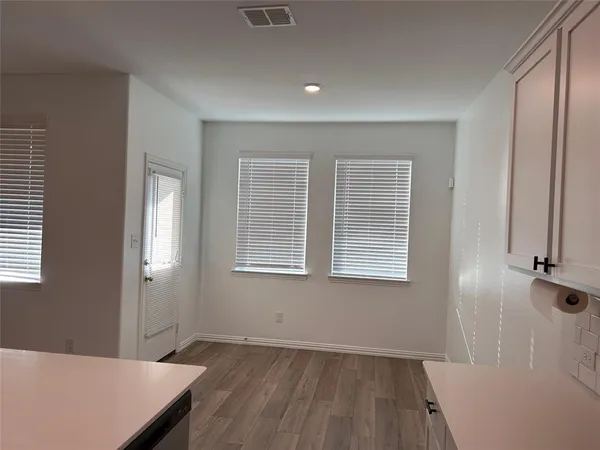 an empty room with wooden floor and windows