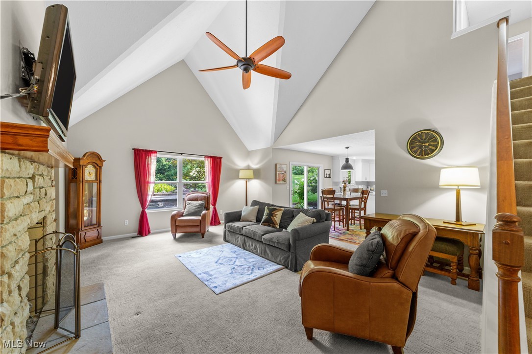 30825 Cannon Road Solon, OH 44139 - Photo 5 of 49 Living room featuring high vaulted ceiling, carpet flooring, stairway, a stone fireplace, and healthy amount of natural light