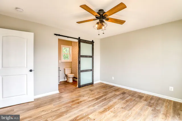 a view of a big room with wooden floor and a chandelier fan