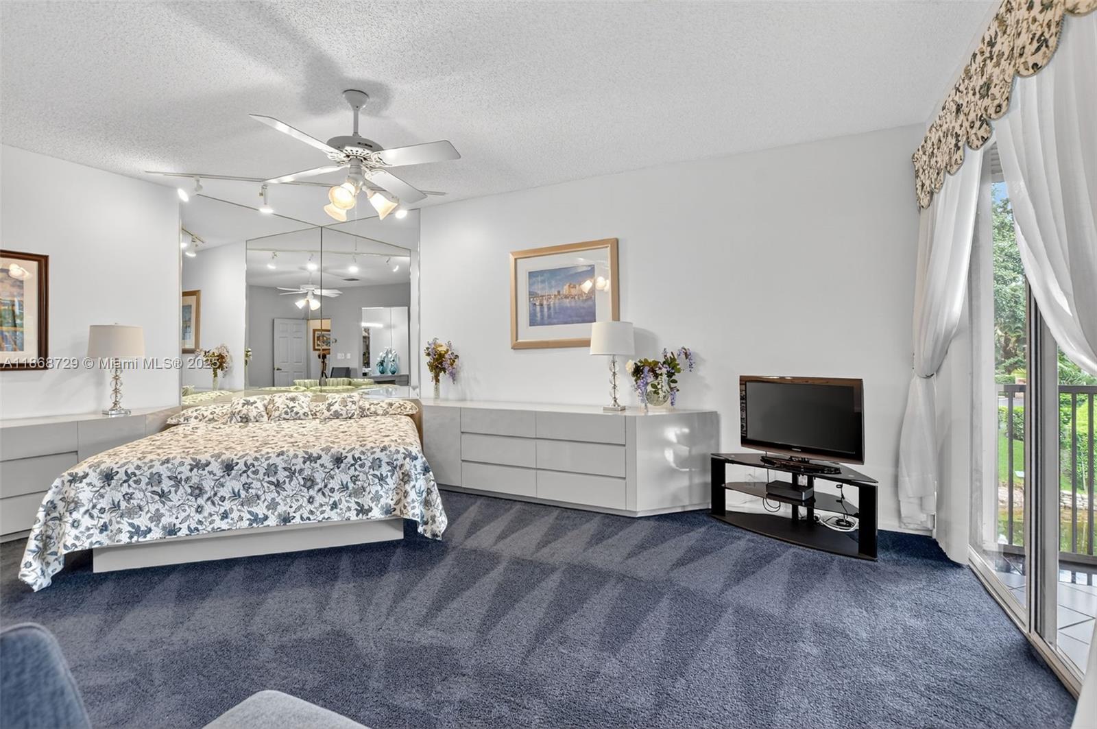 7596 Elm Ridge Drive, Unit 2U Boca Raton, FL 33433 - Photo 16 of 45 a spacious bedroom with a bed and a flat screen tv