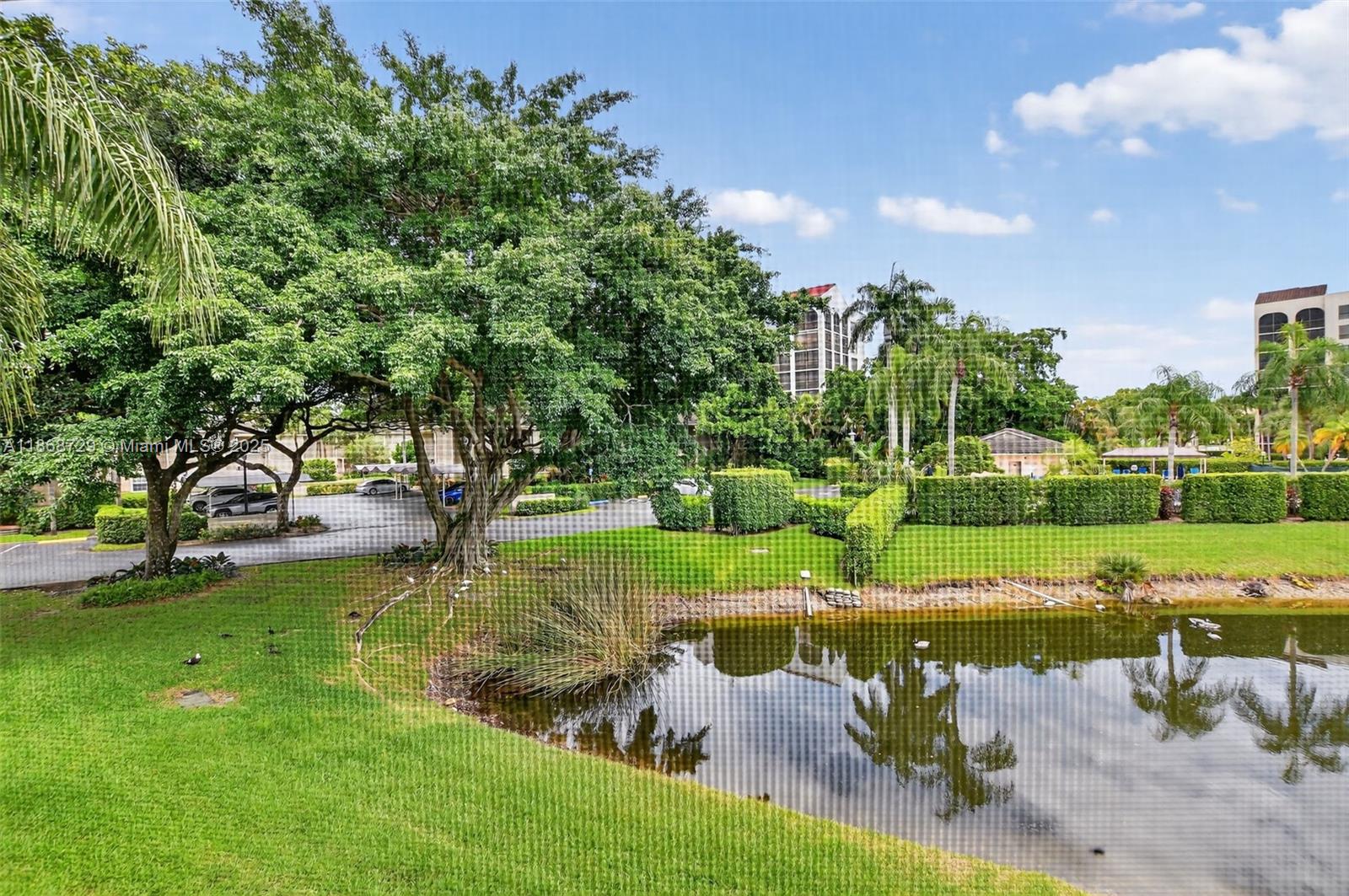 7596 Elm Ridge Drive, Unit 2U Boca Raton, FL 33433 - Photo 34 of 45 a view of a lake with a yard and large trees